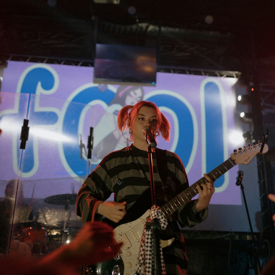A singer with red hair plays electric guitar on stage